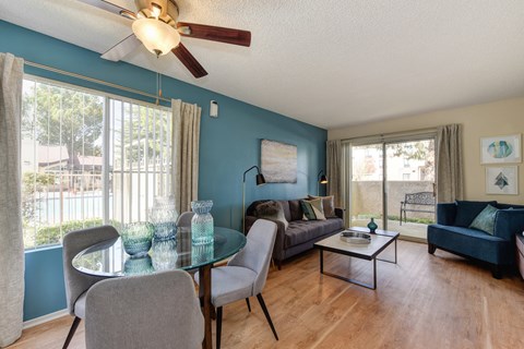 Model home Dining area with round table and chairs.  The living room is in the distance with a sliding glass door leading to the patio area. 